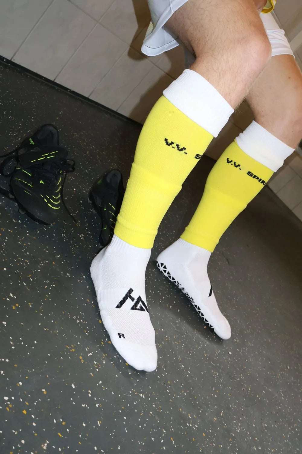 Speler van V.V. Spirit in gele clubsokken met witte HÏ Grip-gripsokken eronder