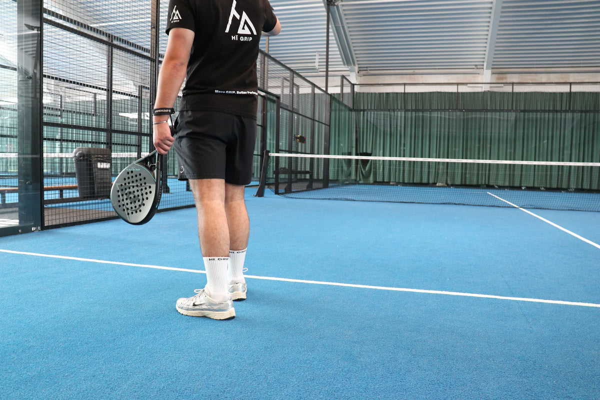 Padelspeler in witte gripsokken op een blauwe padelbaan