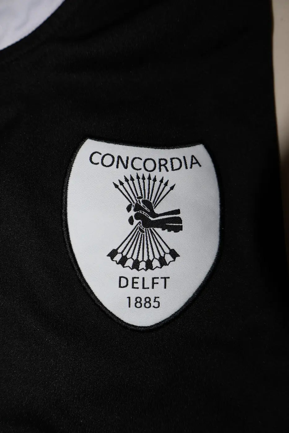 Clublogo van Concordia Delft op een zwart trainingsshirt